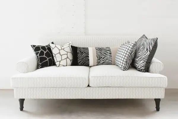 Un divano bianco con cuscini a fantasia animalier e pois: un'idea su come disporre i cuscini sul divano per un tocco moderno.