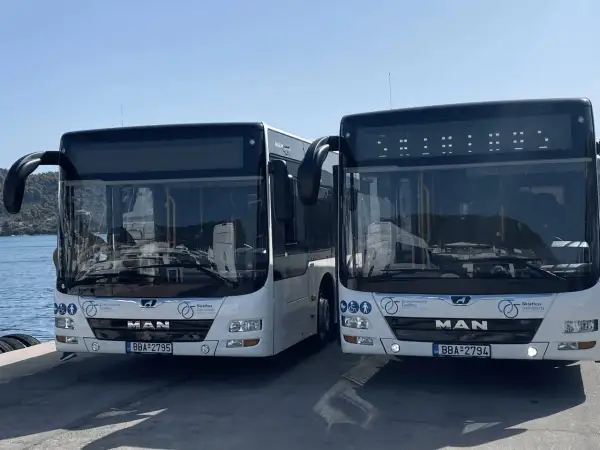 Två vita bussar står redo vid Skiathos flygplats för att transportera resenärer.