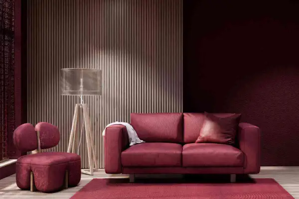 Divano e poltrona in velluto color bordeaux, con tappeto e parete coordinati. Lampada da terra con paralume trasparente.
