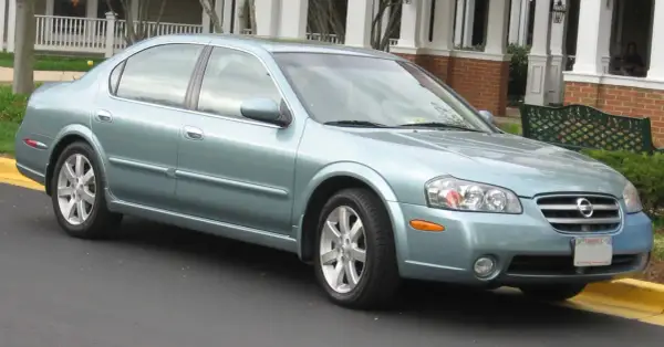 Jasnoniebieski Nissan Maxima 3.5 Turbo stoi przed domem z werandą.
