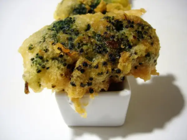 Brocoli en tempura crujiente, servido en un pequeño cuenco blanco con salsa.