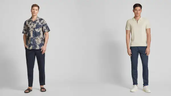 Zwei Männer präsentieren lässige Outfits. Der linke trägt ein gemustertes Hemd zu dunkelblauen Chinos. Der rechte kombiniert ein helles Poloshirt mit denselben blauen Chinos.