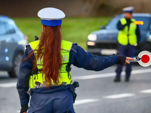Policjantka zatrzymuje ruch, by uniknąć mandatu 24 punkty karne. Inny funkcjonariusz kieruje ruchem.