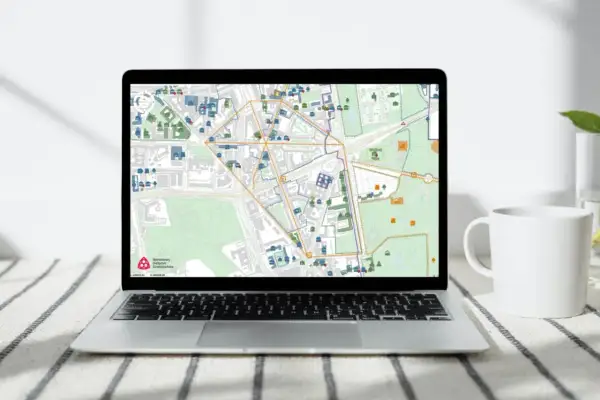 Mapa na ekranie laptopa pokazuje obszar wpisany do rejestru zabytków, z zaznaczonymi budynkami i ulicami.