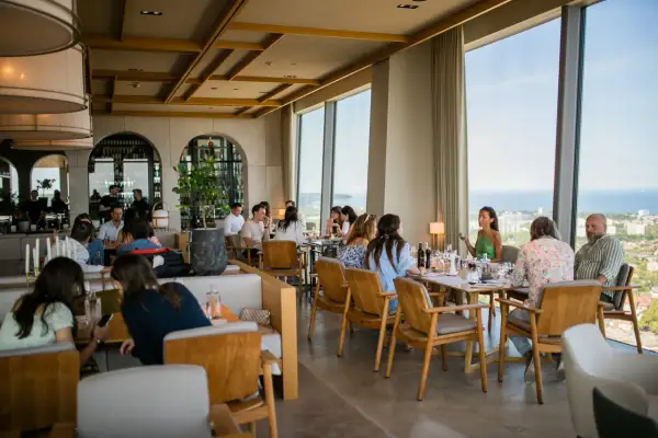 Goście delektują się posiłkiem w restauracji Olivia Star, przeglądając menu i podziwiając widok.
