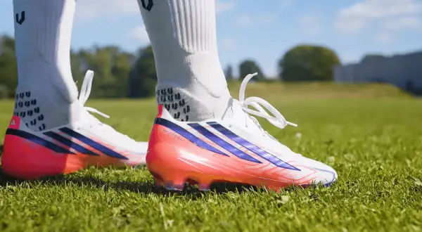 Scarpa calcio Adidas bianca con dettagli blu e rosa fluo. Pronta per scendere in campo e dominare la partita.