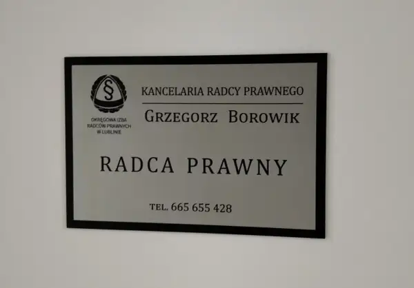 Tabliczka z napisem "Kancelaria Radcy Prawnego Grzegorz Borowik", z logo i numerem telefonu.