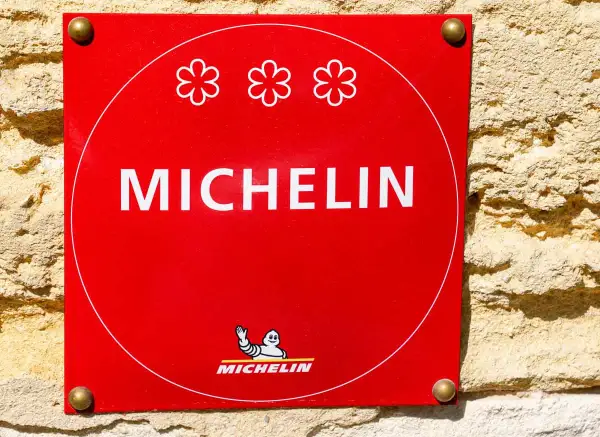 Targa rossa Michelin con tre fiori, simbolo di un ristorante 3 stelle Michelin.