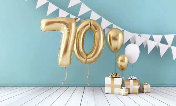 Złote balony z cyfrą 70 i prezenty tworzą piękną scenografię na życzenia na 70 urodziny.