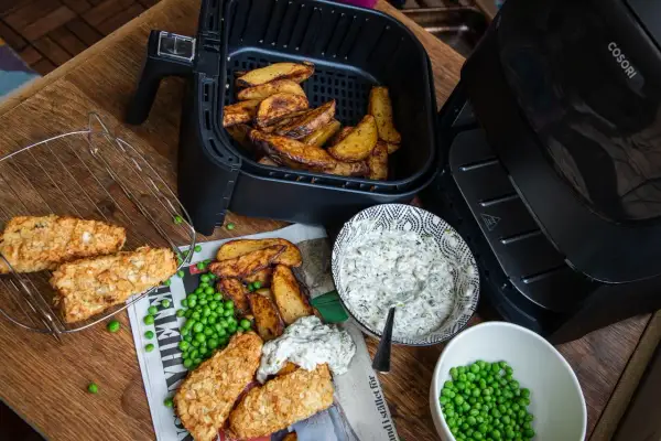 Krispiga fiskpinnar och klyftpotatis från airfryern, serverade med ärtor och en krämig dipp. Ett perfekt airfryer recept!