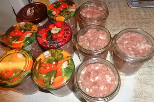 Słoiki z mielonym mięsem, gotowe do pasteryzacji. To pierwszy krok, jak zrobić kiełbasa w słoiku z galaretką.