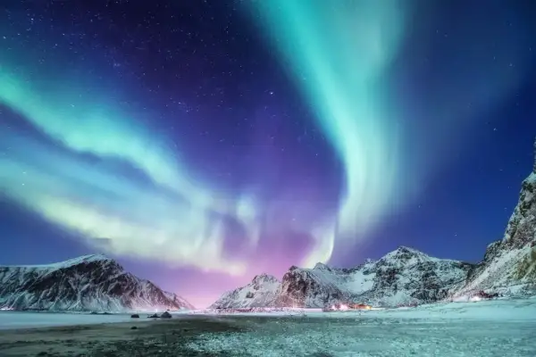 Spektakuläres Nordlicht tanzt über schneebedeckte Berge. Ein magisches Polarlicht-Erlebnis in der arktischen Nacht.