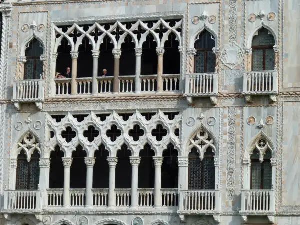 Dettaglio della Ca' d'Oro a Venezia, con le sue finestre traforate e balconi, dove si intravedono persone affacciate.