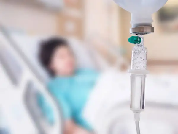 Pacjent w łóżku szpitalnym, kroplówka w zbliżeniu. Trudno określić, który dzień po chemioterapii jest najgorszy.