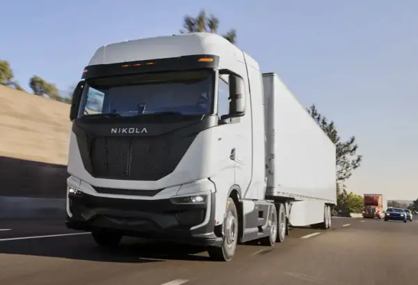 Le Nikola One, un camion blanc futuriste, roule sur l'autoroute sous un ciel bleu clair.