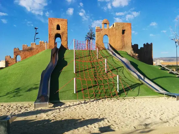 Un castillo de juguete con toboganes y red de escalada en un parque de las familias.