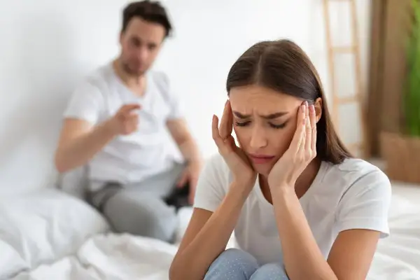 Mujer angustiada, con las manos en la cabeza, mientras su pareja le grita. Siente que mi mujer me maltrata psicológicamente.