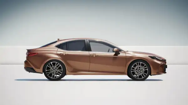 Elegancka, brązowa Toyota Camry 2.5 Hybrid w profilu, prezentująca nowoczesny design i dynamiczną sylwetkę.