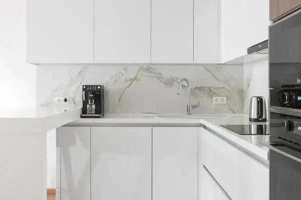 Cucina moderna con mobili bianco lucido e piano in marmo. Si nota la differenza tra il bianco lucido e opaco.