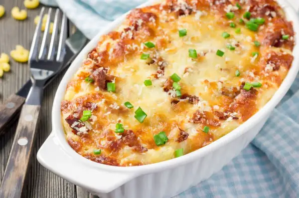 Zapiekane mac and cheese z chrupiącym serem i zieloną cebulką, gotowe do podania.