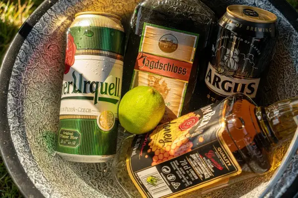 Puszki piwa i butelka whiskey w misce. Zastanawiasz się, ile chmielu do piwa?