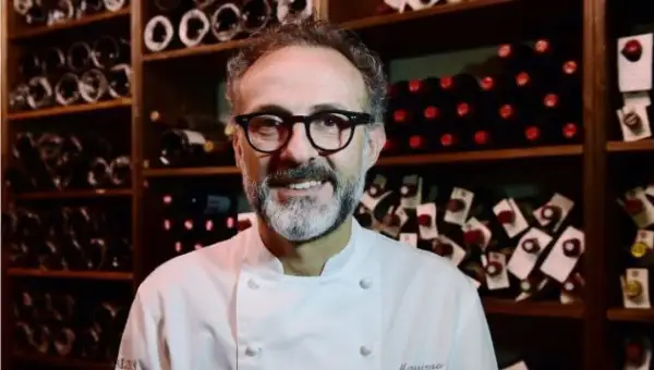 Un sorriso tra gli scaffali di bottiglie di vino, un ritratto di uno dei tanti chef stellati italiani che rendono la cucina italiana famosa nel mondo.