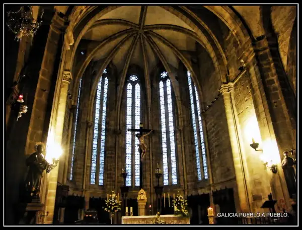 Interior de la iglesia San Francisco de Viveiro, con un crucifijo imponente y vitrales góticos.