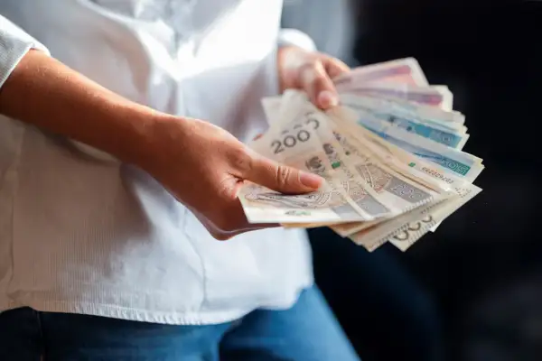 Ręce trzymające polskie banknoty. Zastanawiasz się, jaka będzie najniższa krajowa 2025 i ile na rękę dostaniesz?