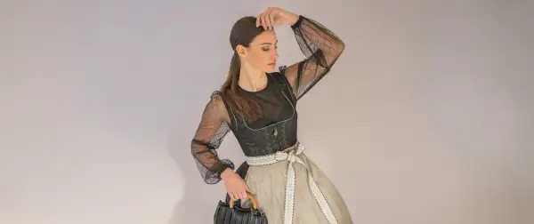 Frau im modernen mini dirndl extra kurz mit transparentem Oberteil und auffälliger Schürze.
