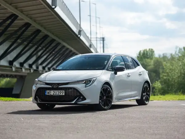 Biała Toyota Corolla GR Sport z czarnymi felgami stoi pod mostem.