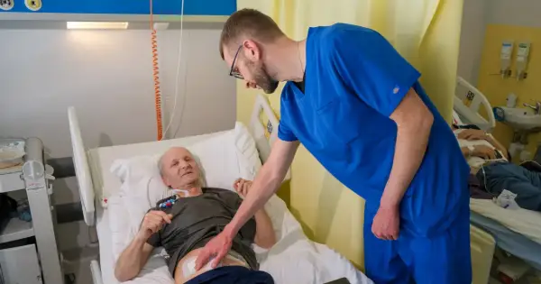Lekarz pochyla się nad pacjentem w łóżku szpitalnym, omawiając jego rokowania po usunięciu trzustki.