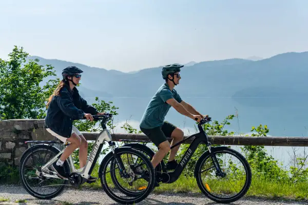 Zwei Personen genießen e bike touren mit Blick auf einen See und Berge.