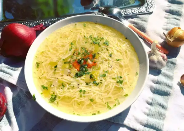 Aromaticzny, złocisty, dobry rosół z makaronem i natką pietruszki, obok cebula i czosnek.