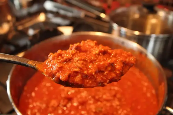 Un cucchiaio di sugo per pasta maritati, denso e saporito, pronto per condire un piatto di pasta fumante.