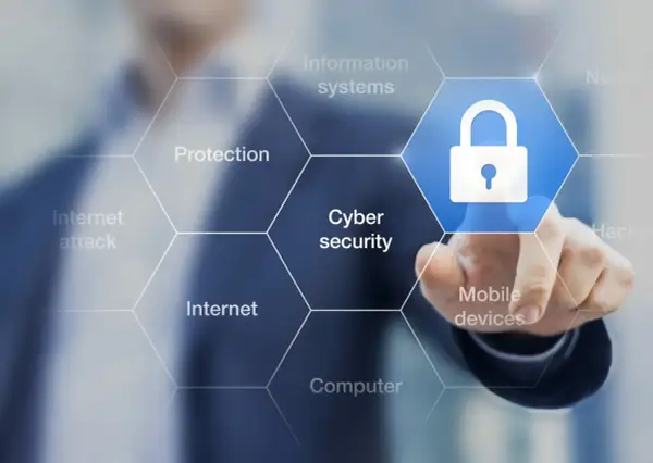 Palec dotyka ikony kłódki, symbolizującej cyberbezpieczeństwo. Wokół widnieją hasła: ochrona, internet, ataki, systemy informatyczne, urządzenia mobilne, komputery. To definicja cyberprzestępczości.