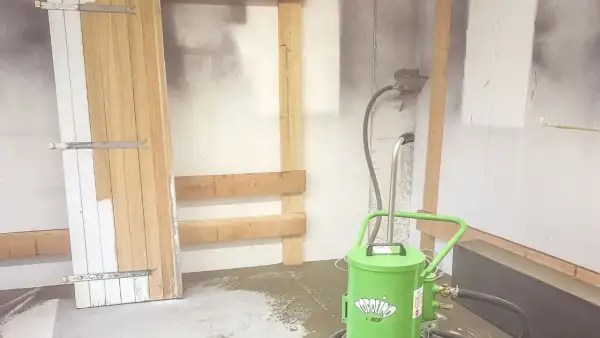 Préparation pour le décapage volet bois : une porte en bois est appuyée contre un mur, avec une machine de décapage à proximité.
