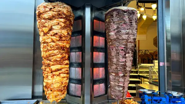 Dwa pionowe rożny z mięsem do kebaba, jeden z kurczaka, drugi wołowy. Zastanawiasz się, ile kcal ma mały kebab?
