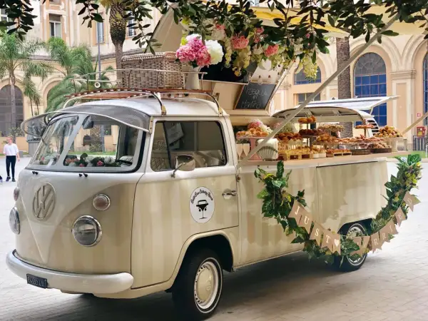 Un furgone vintage allestito per un aperitivo fuori chiesa matrimonio, con fiori e dolci.
