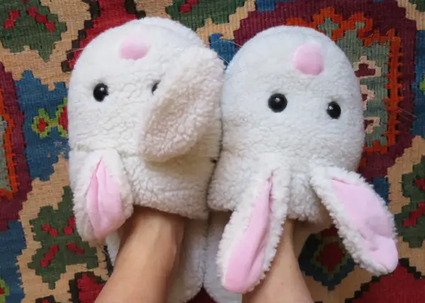 Pantofole a forma di coniglio bianco con orecchie rosa, pronte per essere lavate in lavatrice.