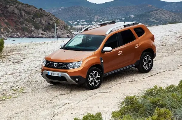 Pomarańczowy Dacia Duster na drodze szutrowej. Wiele osób szuka dacia duster opinie forum, by dowiedzieć się więcej o tym modelu.