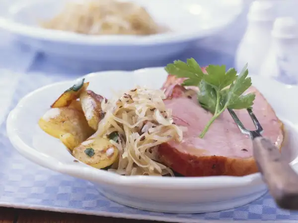 Herzhaftes Fleisch zu bayrisch Kraut mit Bratkartoffeln, garniert mit Petersilie. Ein Klassiker der bayerischen Küche.