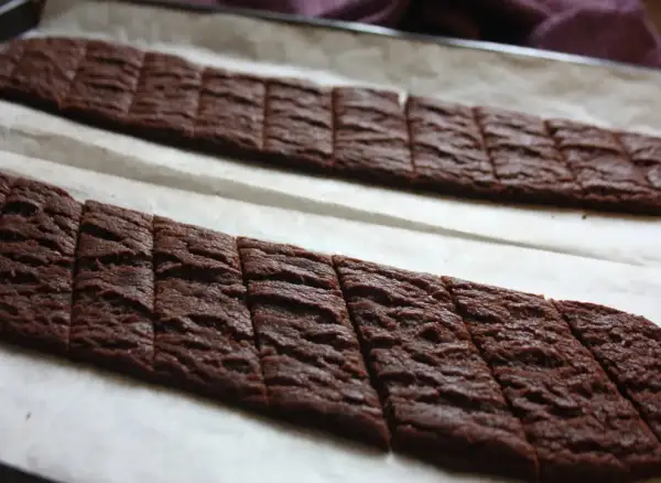 Två rader med sega chokladsnittar på bakplåtspapper, redo att gräddas.
