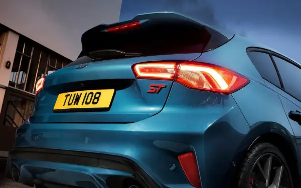 Tylna część sportowego Forda Focus ST 2025 w kolorze niebieskim, z podświetlonymi światłami i czerwonym emblematem ST.