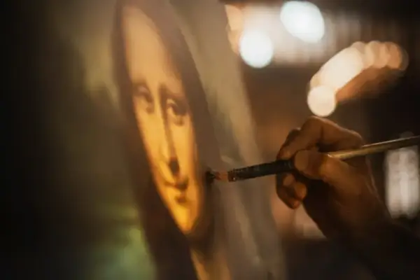 Dłoń artysty dopracowuje słynny obraz Leonarda da Vinci, Mona Lisę, dodając ostatnie pociągnięcia pędzlem.