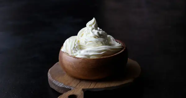Kremowy mascarpone w drewnianej miseczce, idealny do deserów. Warto sprawdzić mascarpone kcal przed przygotowaniem słodkości.