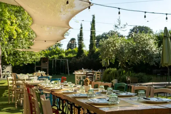 Tavoli apparecchiati all'aperto in un giardino lussureggiante, un'atmosfera perfetta per scoprire i migliori ristoranti a Firenze.
