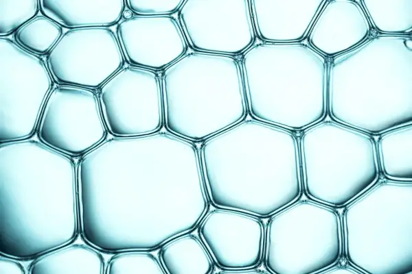 Nahaufnahme von Seifenblasen, die ein wabenartiges Muster bilden. Pentylene Glycol sorgt für die Stabilität dieser Struktur.