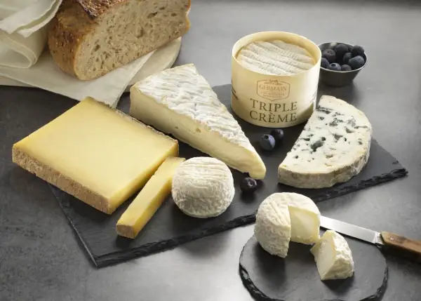 Plateau de fromages variés, dont un bleu et un triple crème, accompagnés de pain artisanal. Un délice pour les amateurs de fromage fort en goût.