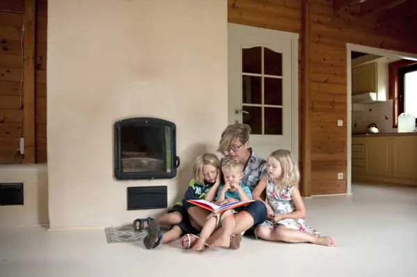 Een moeder leest voor aan haar drie kinderen bij de open haard. Een moment van rust en samenzijn, ontspullen voor en na een drukke dag.