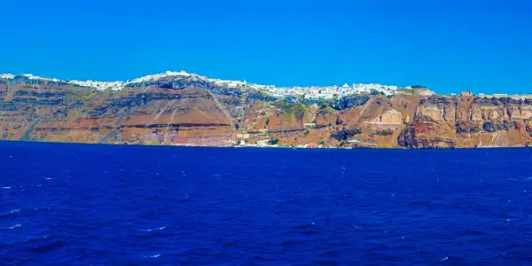 Widok na białe miasteczko na klifie nad błękitnym morzem na Santorini.